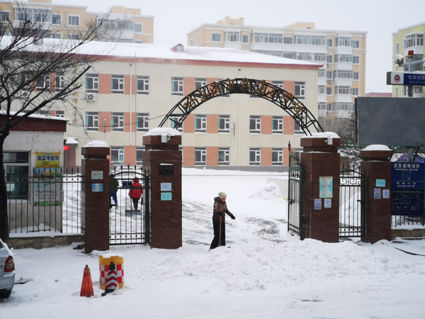 2021年11月22日,哈尔滨市钱塘小学的老师在校园内清雪.