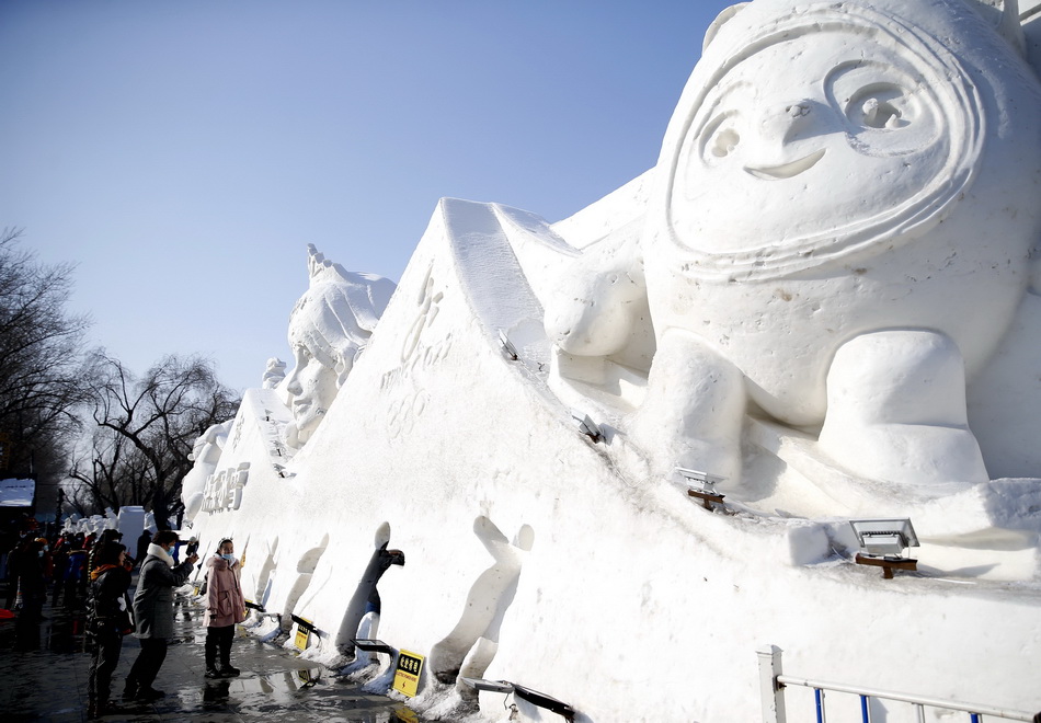 2月8日,黑龙江哈尔滨,游客在防洪纪念塔广场冰墩墩雪雕前拍照.