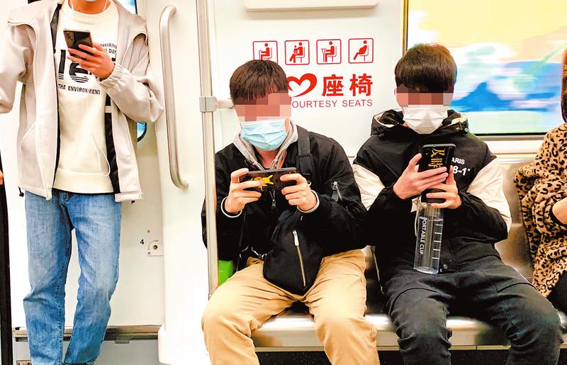 南宁地铁上有不少乘客玩手机。南宁晚报 图