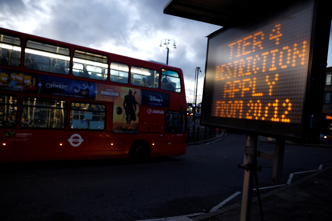  12月20日，在英国伦敦，一辆巴士经过显示“12月20日起实施新冠疫情防控级别第四级”字样的电子屏。新华社 图