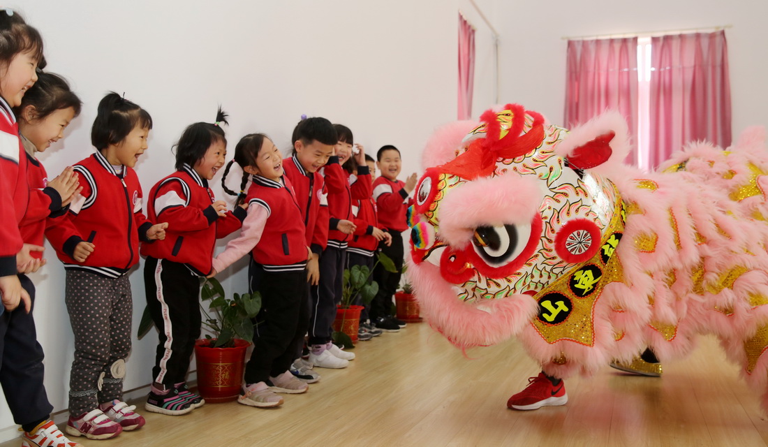 12月24日,山东省东营市东营区文华幼儿园的孩子们与舞狮艺人互动.