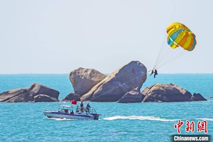 游客在天涯海角体验海上拖伞项目。