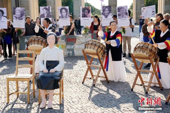 2019年8月14日，在德的韩国和日本民间团体在柏林勃兰登堡门前集会，敦促日本政府正式向“慰安妇”制度暴行受害者道歉。一座“和平少女像”亦出现在当天活动现场。中新社记者 彭大伟 摄