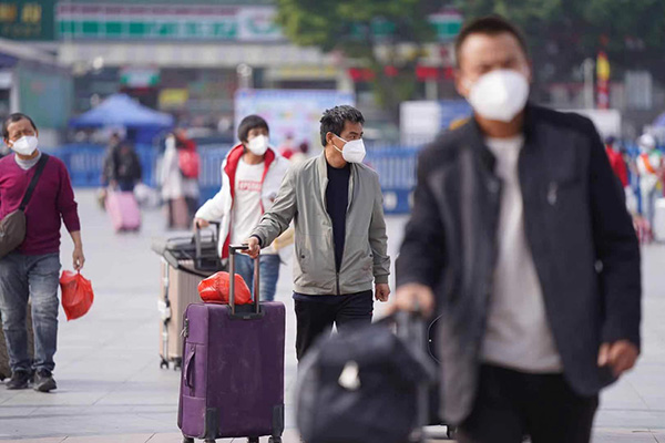 2021年1月28日，春运首日，拖着行李回家的旅客准备进入广州火车站。人民视觉 图