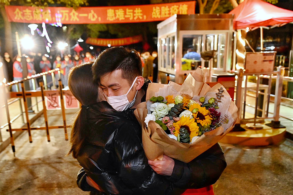 2021年2月19日，上海市浦东新区新高苑，黄思杰与前来送花的老婆相拥。新高苑封闭期间，在高东镇镇政府工作的黄思杰在新高苑内做志愿者。