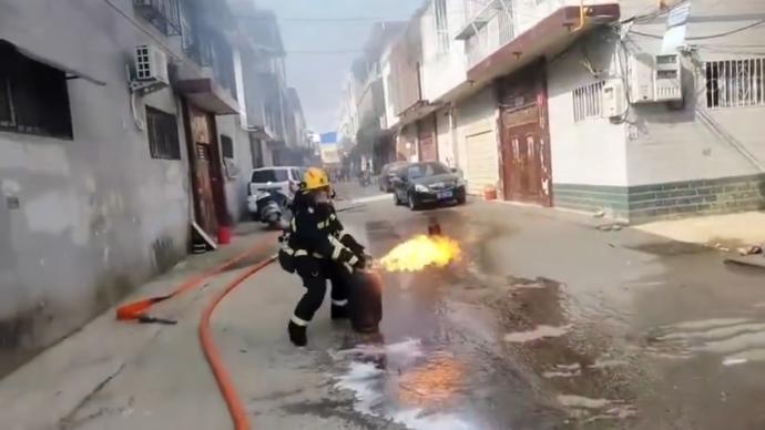 消防員徒手拎出燃燒的煤氣罐，戰友用水幫他手部降溫