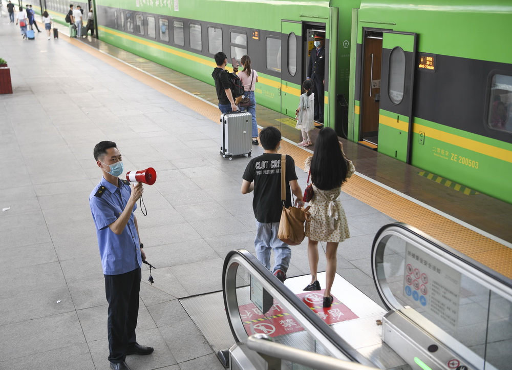 5月1日,重慶火車站工作人員在站臺扶梯口引導旅客有序上車.