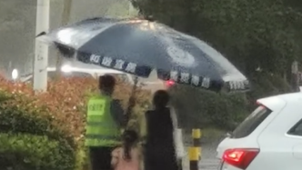 暴雨中，辅警为母女撑起大号雨伞