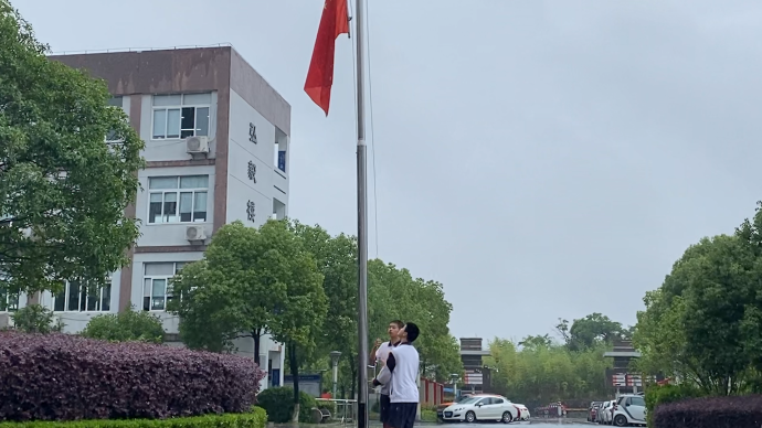 风雨大作校内国旗被吹落，两名男生冒雨捡起