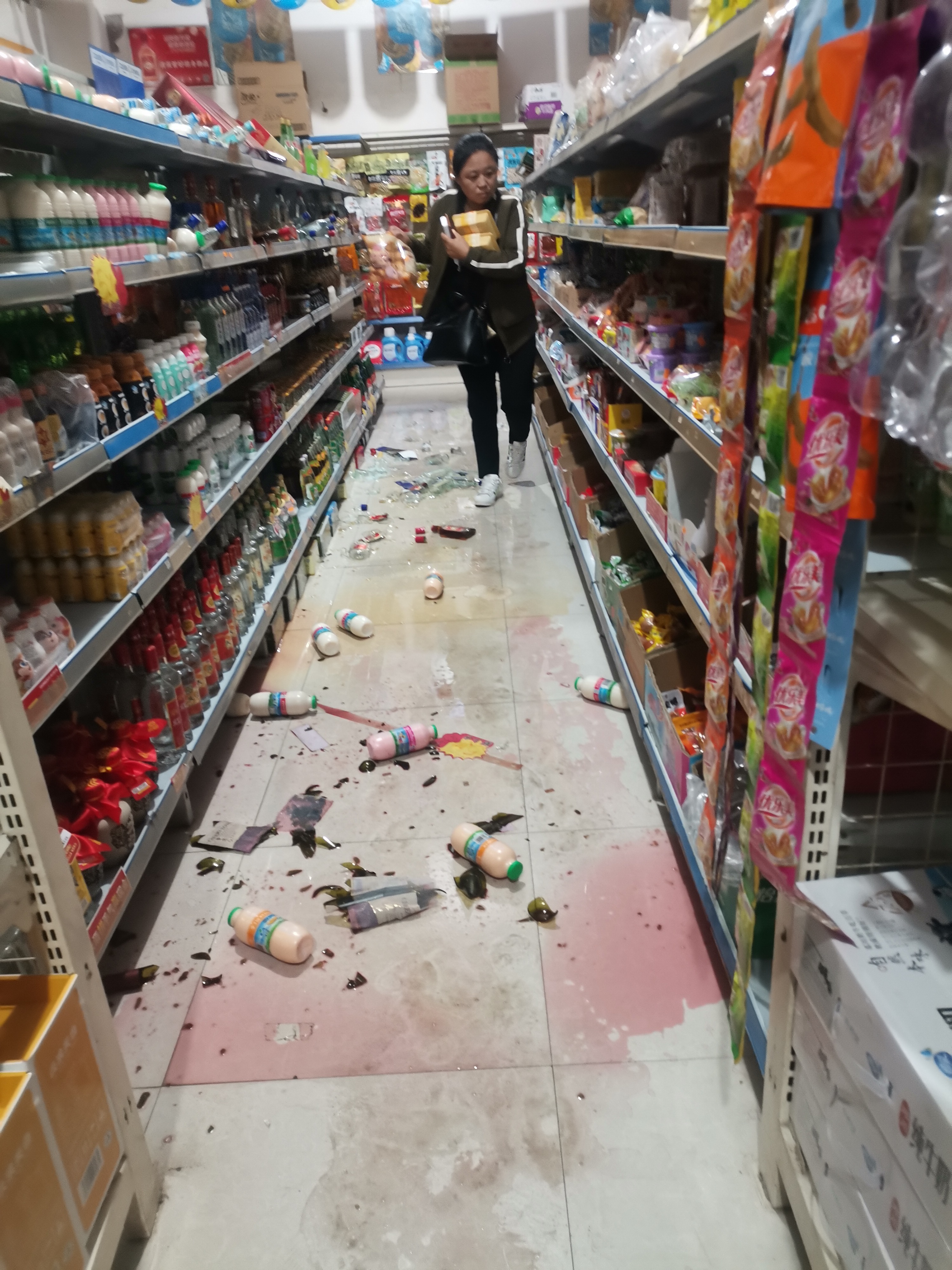 地震时,超市地面出现晃动,货物震落在地上,正在排队的顾客纷纷向外跑
