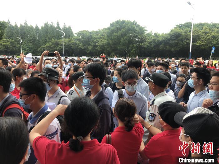 资料图：2020年全国高考期间，上海某考场外，老师们穿着红色T恤站在考场入口处为考生们送上祝福。叶颖 摄