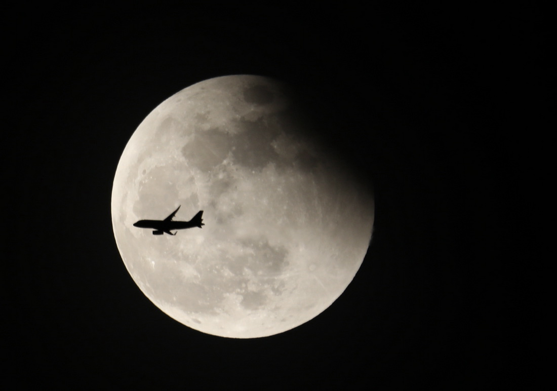 2021年5月26日20时50分许,广东珠海,一架飞机从正在复圆的月亮下飞过.