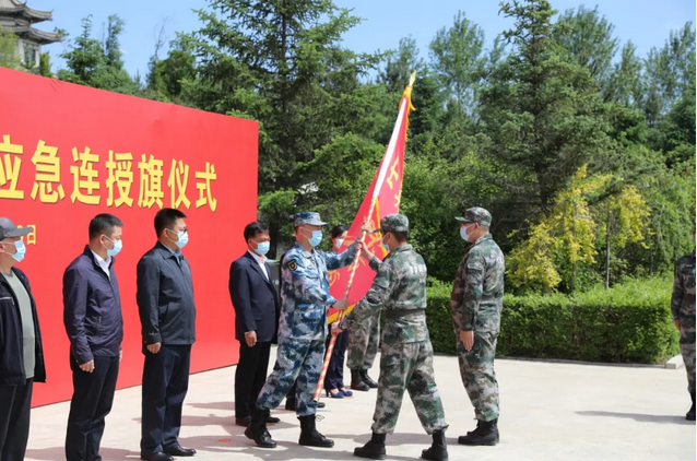 扶余市士英民兵连连长蓝海从军分区政委马永健手中接过连旗.