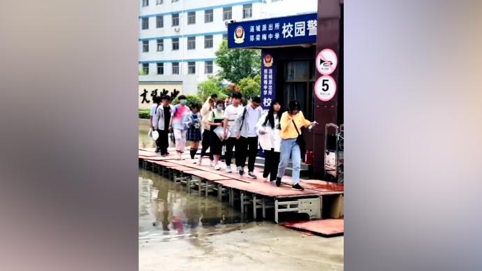 暴雨后校园积水，学生踩“课桌桥”进考场