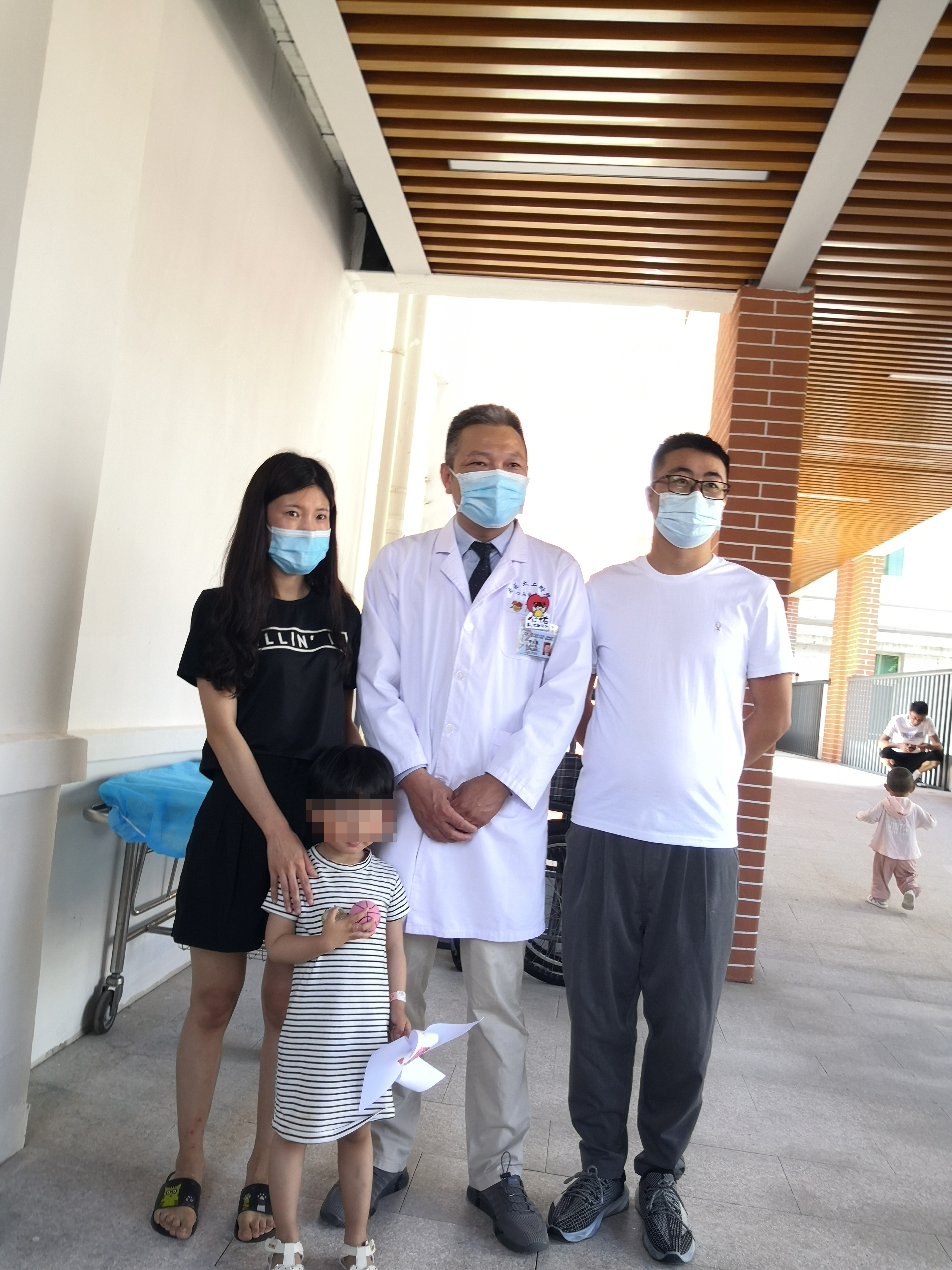 手术治疗康复后，小伊伊一家三口与李庆国医生合影留念。