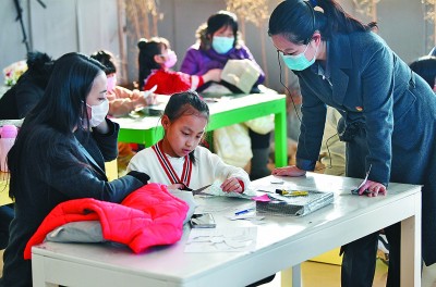 在天津博物馆，小朋友在老师和家长的注视下裁剪布料。 新华社发