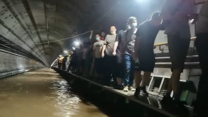 郑州地铁隧道内救援画面：乘客从水中脱身走上沿边小道
