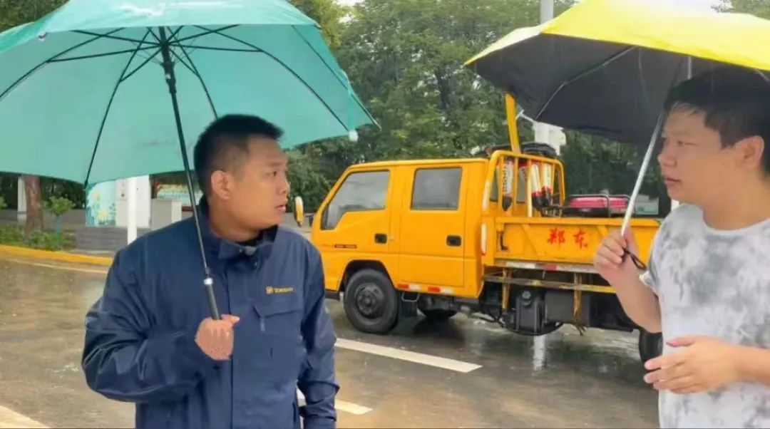 郑州经济广播记者袁铭阳(右)在商务西八街地铁会展中心站C口现场报道积水情况。