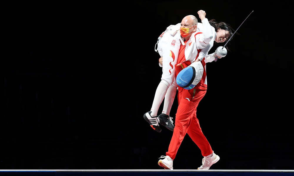 北京时间7月24日，在东京奥运会击剑项目女子个人重剑决赛中，中国选手孙一文（右）以11比10战胜罗马尼亚选手波佩斯库，夺得冠军，法国外教雨歌·欧伯利一把将孙一文扛在肩上，最后还给孙一文披上五星红旗。