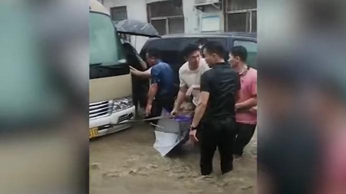河南安阳：村民洪水中合力拽出载满儿童的中巴车