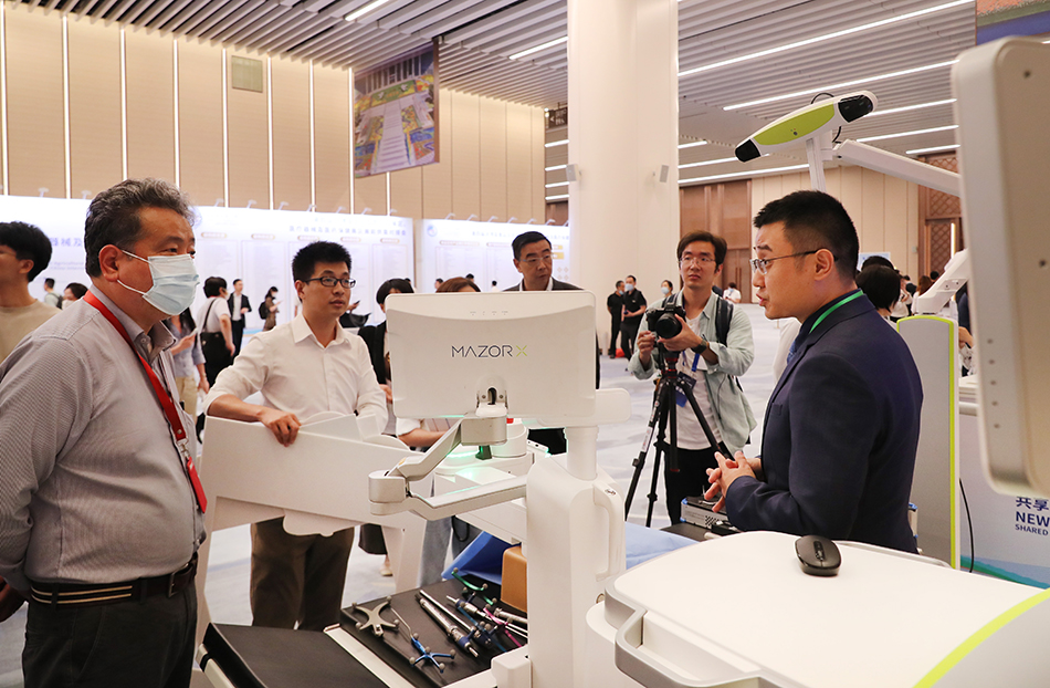 2021年7月26日,第四届进博会部分展区展前供需对接会在上海举行,图为参展企业工作人员(右一)和参会嘉宾在展台前交流。 新华社记者 方喆 摄