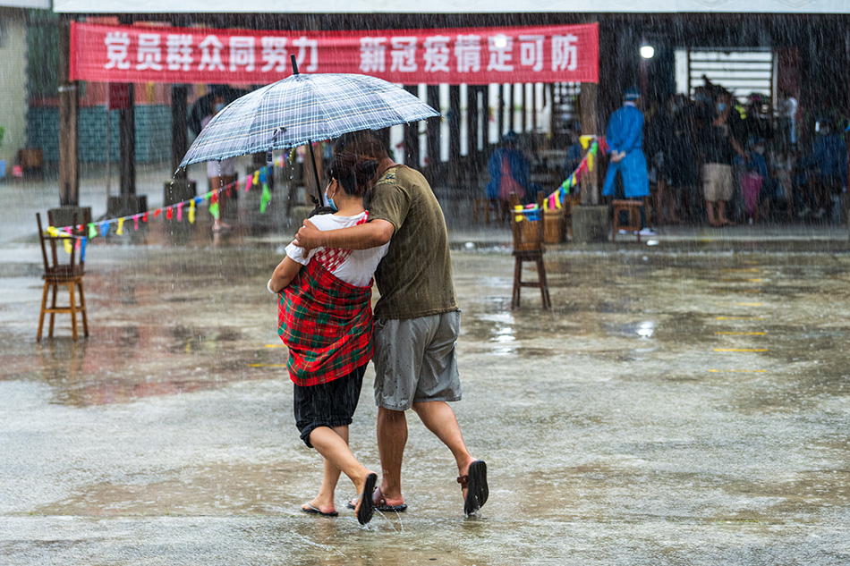 2021年8月1日,云南省瑞丽市一村社内,村民核酸检测后冒雨回家.