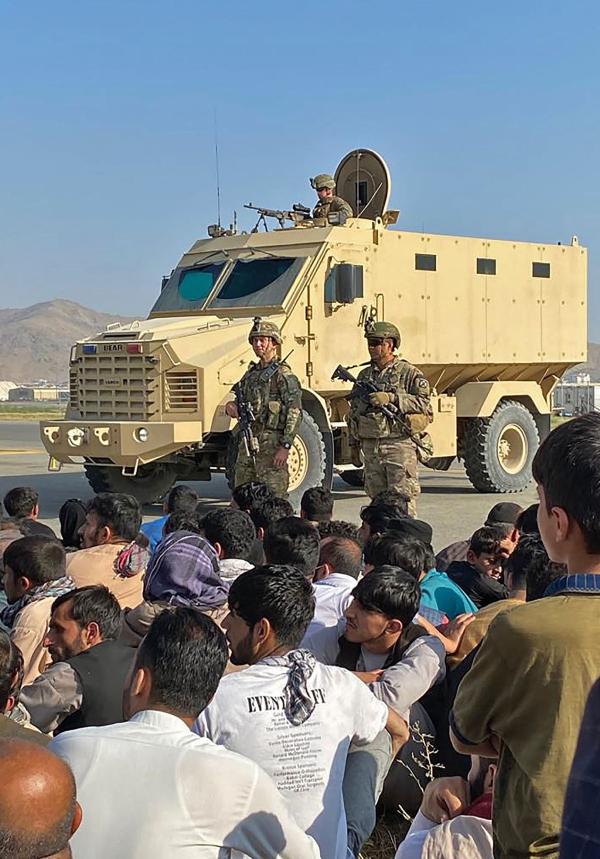 当地时间2021年8月16日，阿富汗，乘客挤在机场等待离开喀布尔，美国士兵站岗。