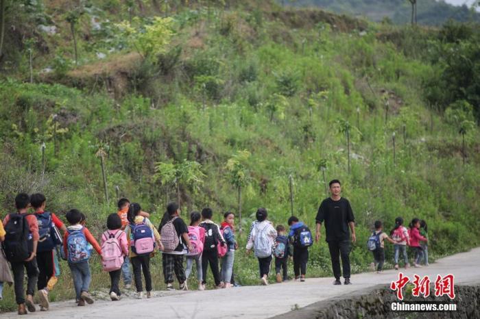 资料图：一名“90后”乡村教师组织学生排队上下学。中新社记者 瞿宏伦 摄