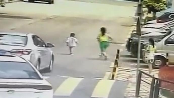 幼兒誤闖車流,小學女生沖上馬路將他抱回