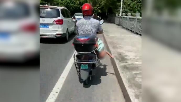 广西钦州一男子骑电动车倒挂孩子，交警已介入调查