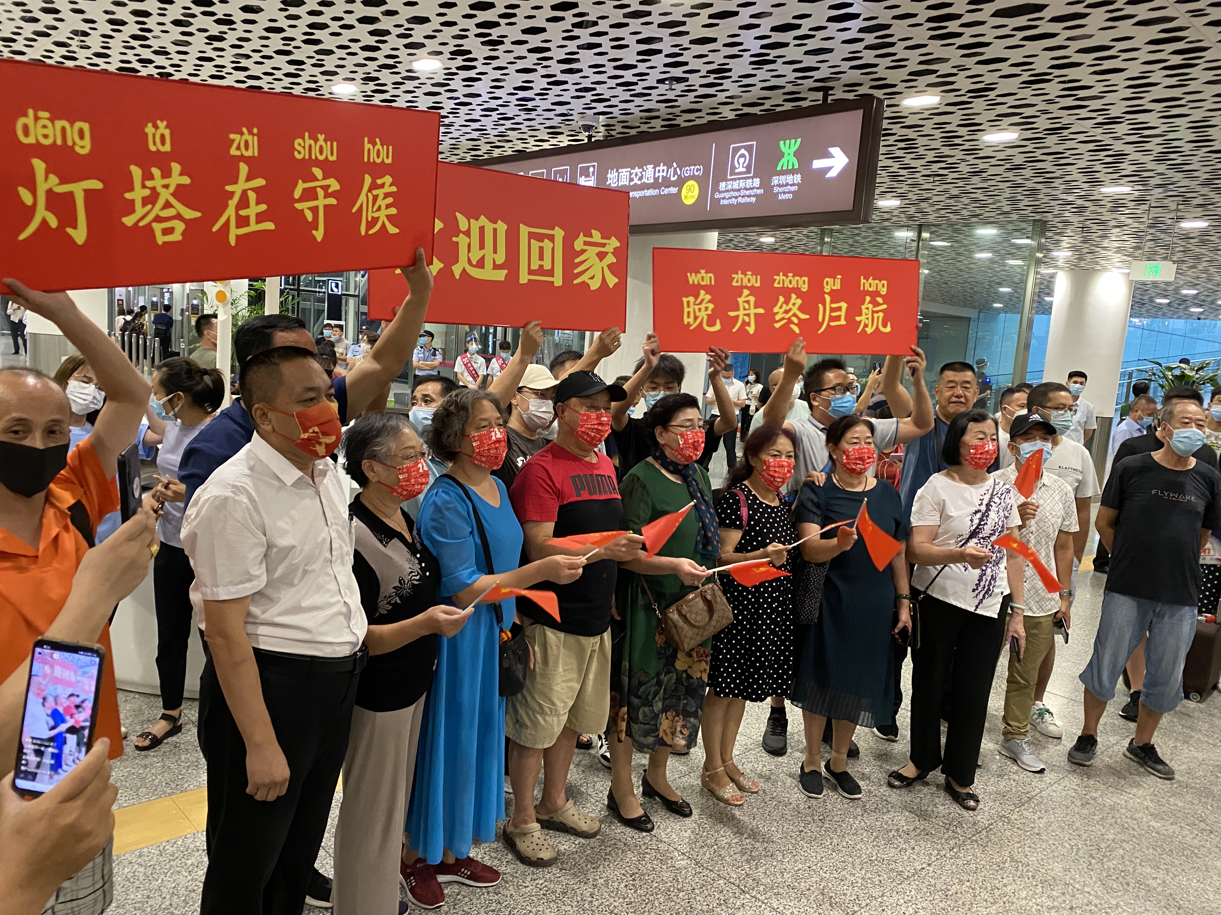 澎湃新闻记者在深圳宝安国际机场看到各地爱国群众手举横幅,共同迎接