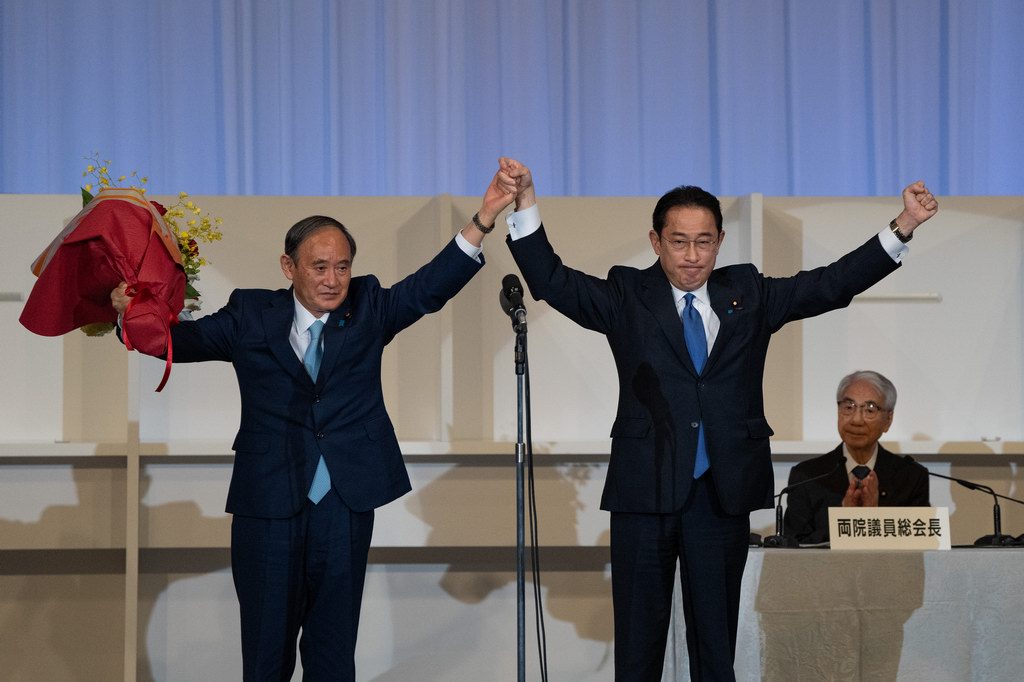 雄(前右)在日本东京当选自民党总裁后接受日本首相菅义伟(前左)的祝贺