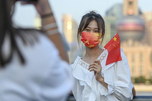 一位女生拿着五星红旗在外滩留影.