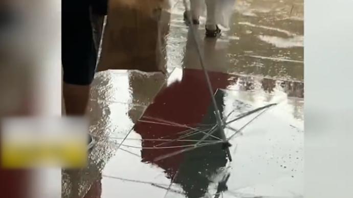 台风来袭小伙雨伞吹得只剩架子，伞布吹到身上秒变“雨衣”