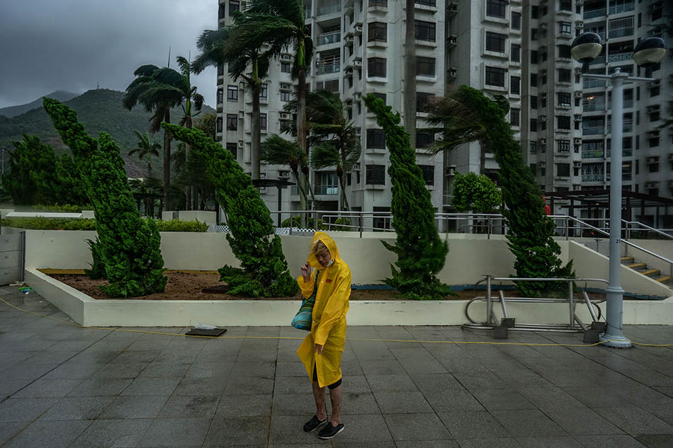2021年10月13日，中国香港，一名男子在街头裹紧雨衣抵挡强风。受台风“圆规”影响，香港天文台当天宣布，八号东北烈风或暴风信号仍然生效，香港多项公共服务和社会活动暂停。Anthony Kwan/视觉中国 图