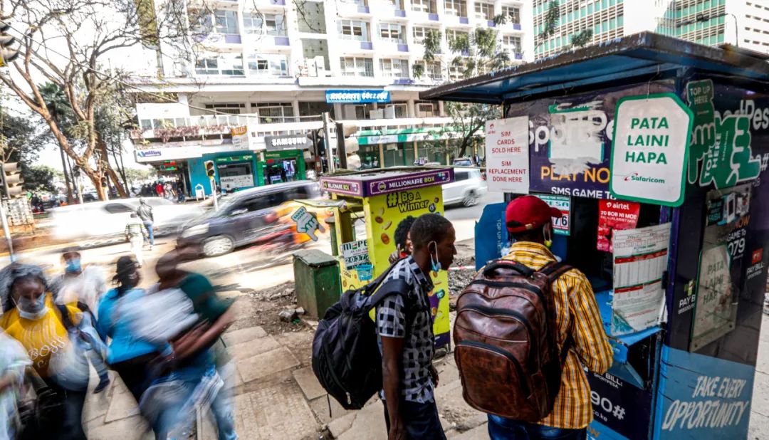 2021年9月16日，肯尼亚首都内罗毕市中心，人们站在一处M-Pesa代理网点。新华社记者 张宇 摄