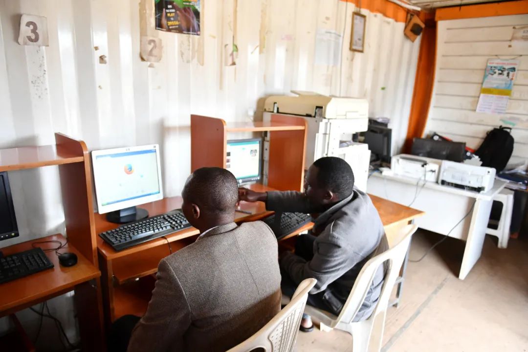 2016年11月18日，在肯尼亚首都内罗毕的基贝拉贫民窟，两名男子在一家网吧上网。新华社记者 孙瑞博 摄