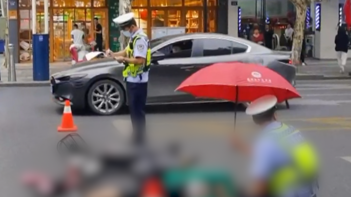 电动车车主受伤倒地，交警借伞蹲在地上为其遮雨