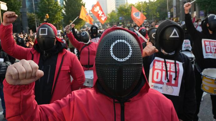 韩国爆发万人罢工集会，抗议者穿《鱿鱼游戏》同款服装游行