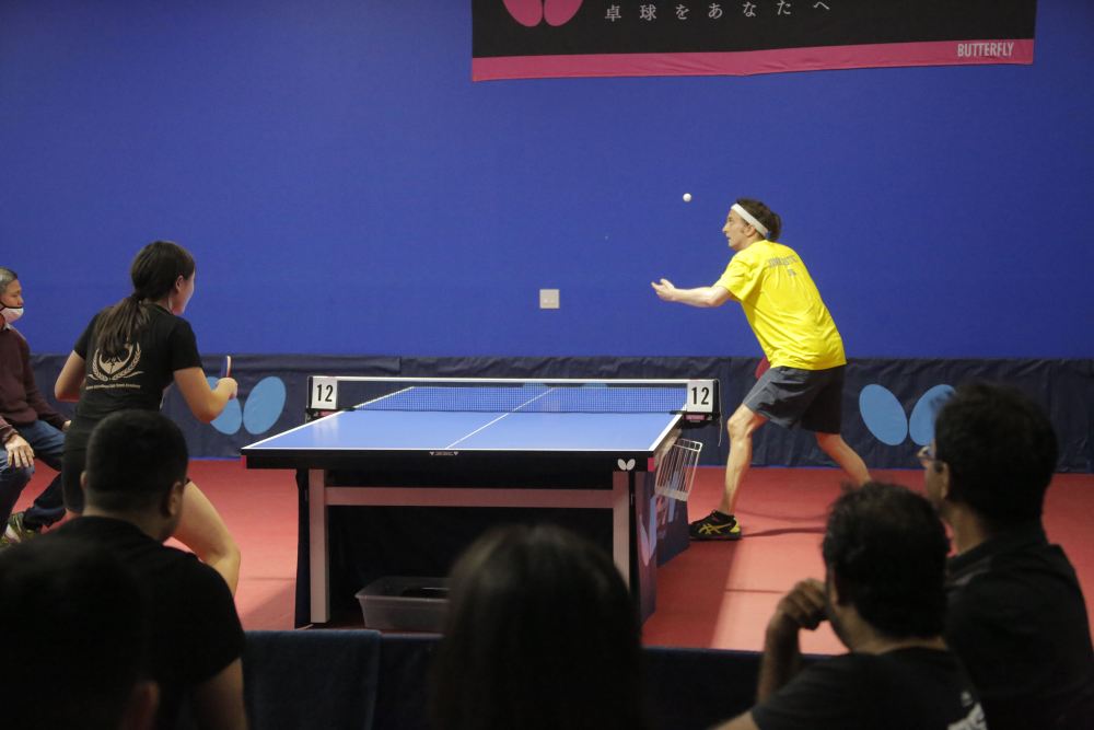 11月13日, 前美国乒乓球冠军吉姆·巴特勒在休斯敦一家乒乓球馆与美国青少乒乓球队员宋恩比赛。新华社发（劳承跃摄）