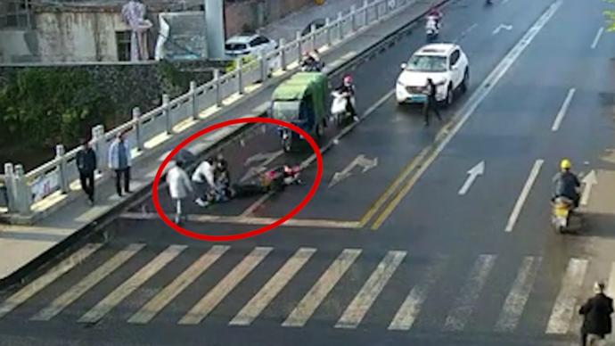 骑行女子刹车减速避让行人摔倒，众人上前救助
