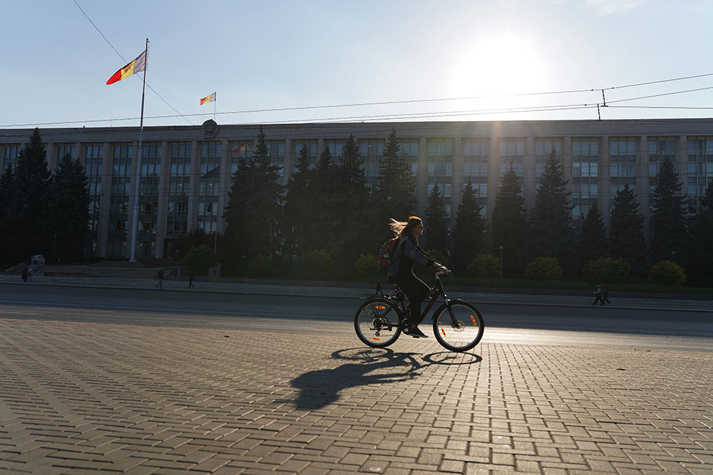 当地时间2021年10月28日，摩尔多瓦基希讷乌，一名女子骑着自行车经过摩尔多瓦政府大楼。人民视觉 图