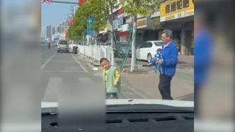 孩子用棍子牵盲人老爷爷过马路，老人帮他拿着奥特曼玩具