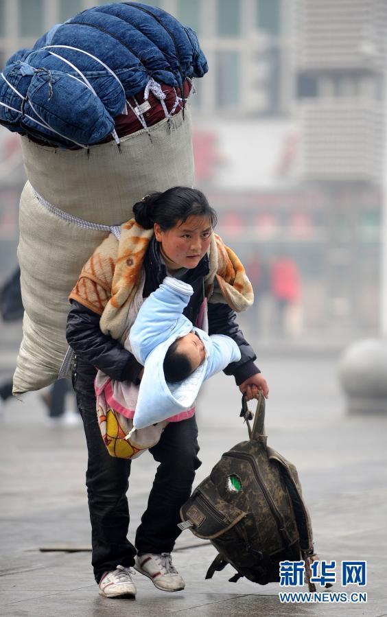 2010年1月30日，巴木玉布木背着大包、抱着孩子在南昌火车站匆忙赶车。新华社记者 周科 图