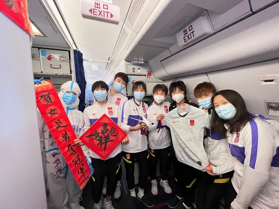 2月7日，中国女足主教练水庆霞（右三）和部分队员在机舱内与空乘人员合影。新华社发（中国东方航空供图）