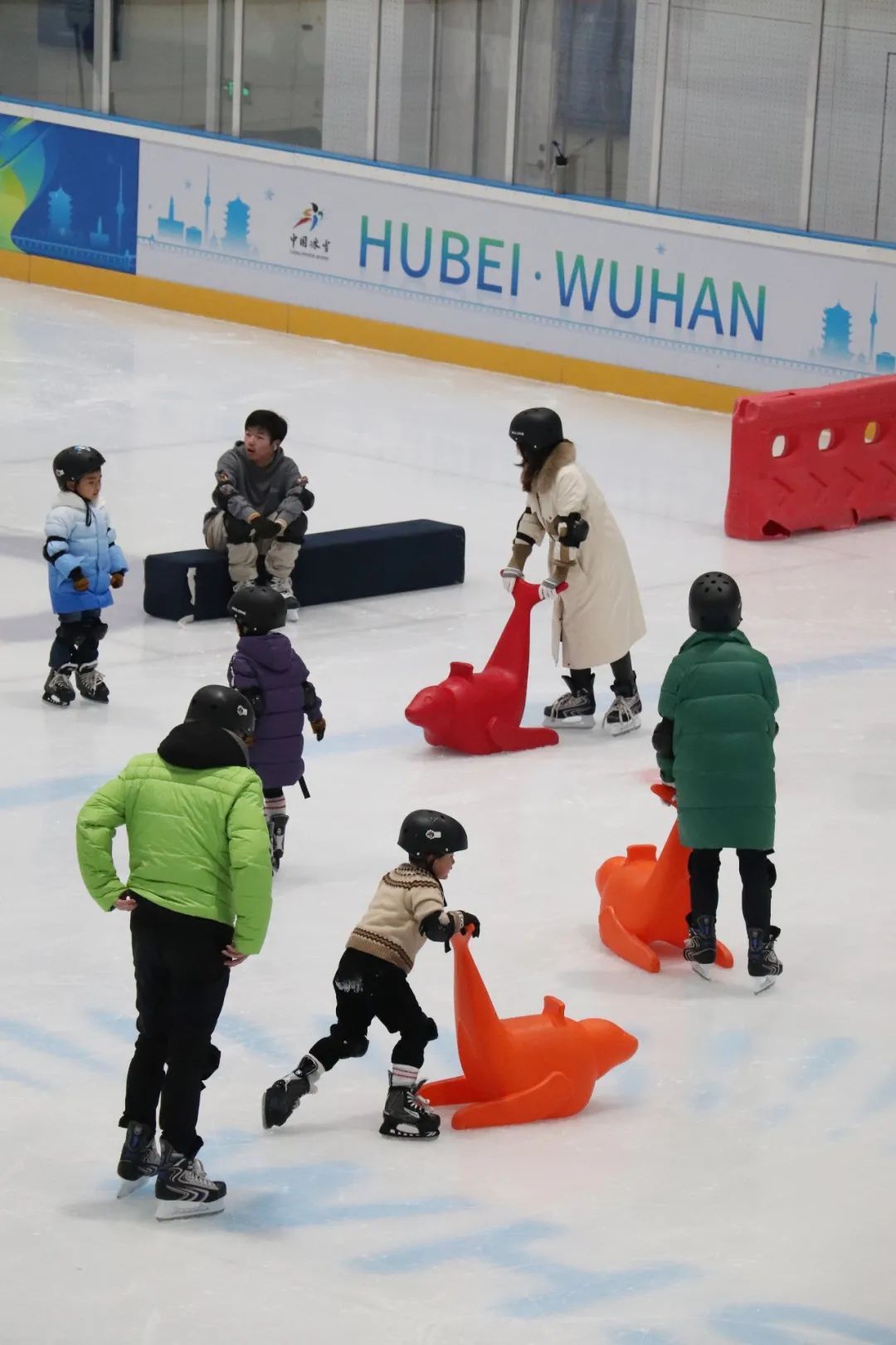 武汉冰上运动中心的冰场上熙熙攘攘,许多市民与亲友一起体验冰雪运动