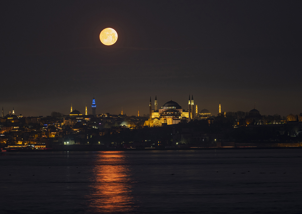 当地时间2022年2月15日，土耳其伊斯坦布尔， 一轮满月出现在当地的地标建筑圣索菲亚大教堂以及苏莱曼尼耶清真寺上空。