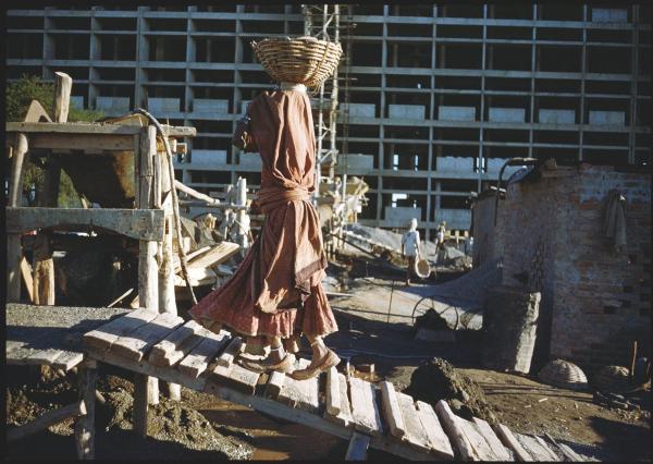 1956年，在印度昌迪加尔勒·柯布西耶设计的国会大厦，一名妇女在秘书处前搬运水泥。 图：Ernst Scheidegger, via Museum of Modern Art, New York