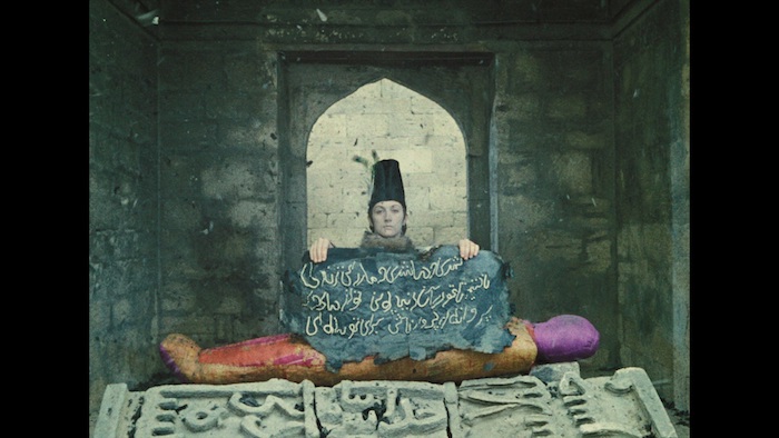 《石榴的颜色》剧照。安娜公主在“墓穴“及第起写着宛若是阿拉伯字母的黑纸。此时背景起头响起那两句诗——“我们将你埋上全国，以便你在来世化蝶”。第一遍用的是格鲁吉亚语。内景地位于阿塞拜疆巴库内城处女塔下方，古代已经是地下露天市场，往常是露天博物馆。