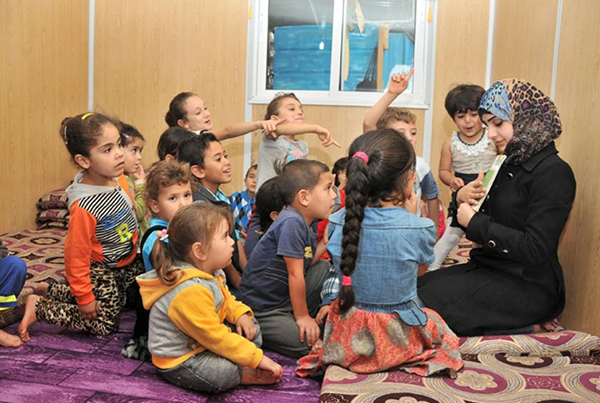 难民Asma给孩子们阅读，她16岁结婚，和丈夫及两个孩子从叙利亚逃到约旦的难民营。